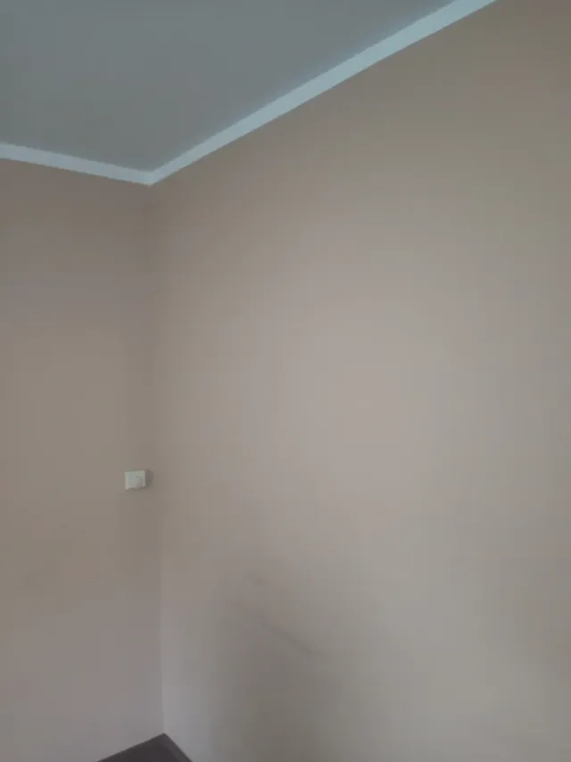 Ściana pokryta gładzią gipsową z równym narożnikiem i listwą sufitową, realizacja w Krakowie